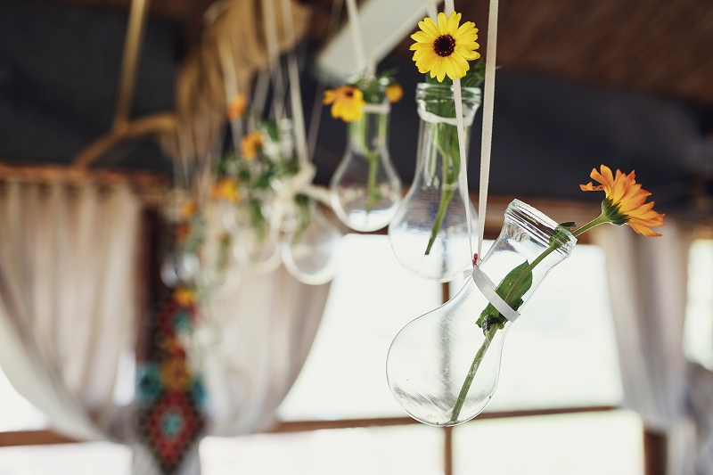 Pequeños jarrones con flores colgados como decoración